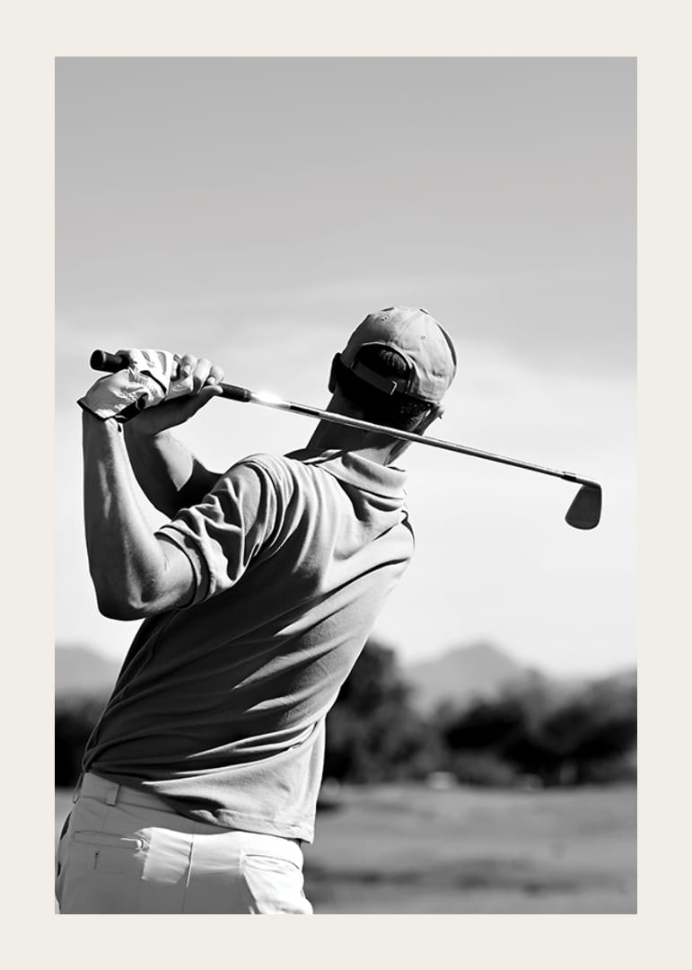 Fekete-fehér golfozó lendületes klubbal a fényes égbolt ellen-12