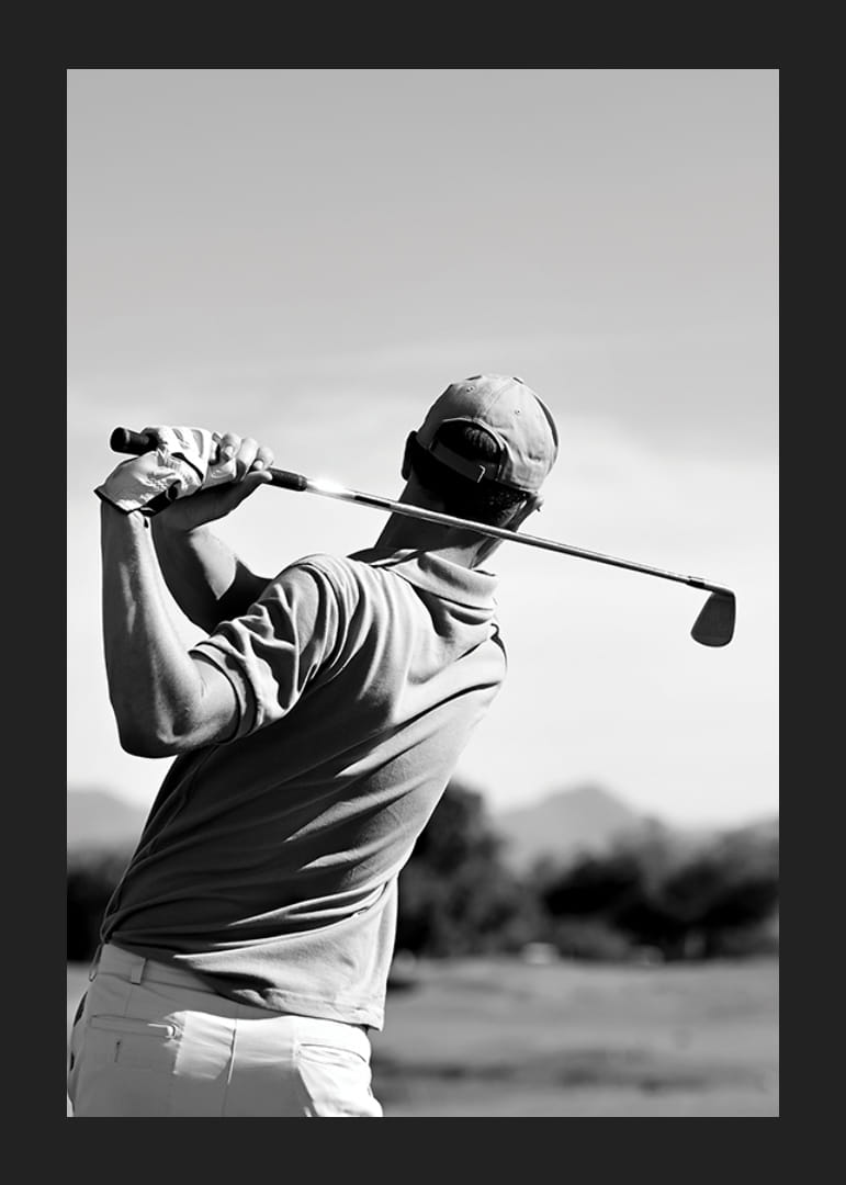 Fekete-fehér golfozó lendületes klubbal a fényes égbolt ellen-12