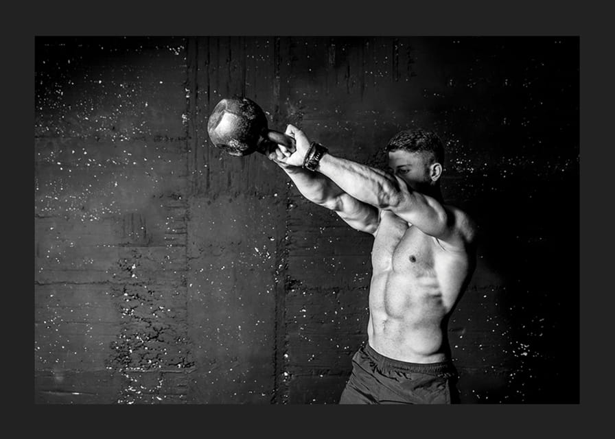 Gros plan noir et blanc d'un homme faisant de l'exercice avec une kettlebell contre un mur en béton brut-12