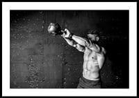 Black and white close-up of man exercising with kettlebell against raw concrete wall-2