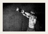 Black and white close-up of man exercising with kettlebell against raw concrete wall-5