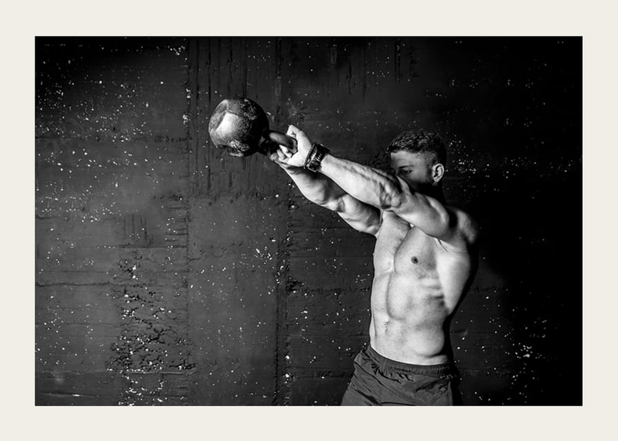 Gros plan noir et blanc d'un homme faisant de l'exercice avec une kettlebell contre un mur en béton brut-12