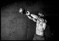 Black and white close-up of man exercising with kettlebell against raw concrete wall-6
