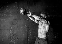 Black and white close-up of man exercising with kettlebell against raw concrete wall-7