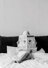 Black and white photo of woman in bathrobe reading newspaper in bed-7