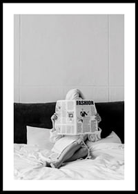 Black and white photo of woman in bathrobe reading newspaper in bed-0