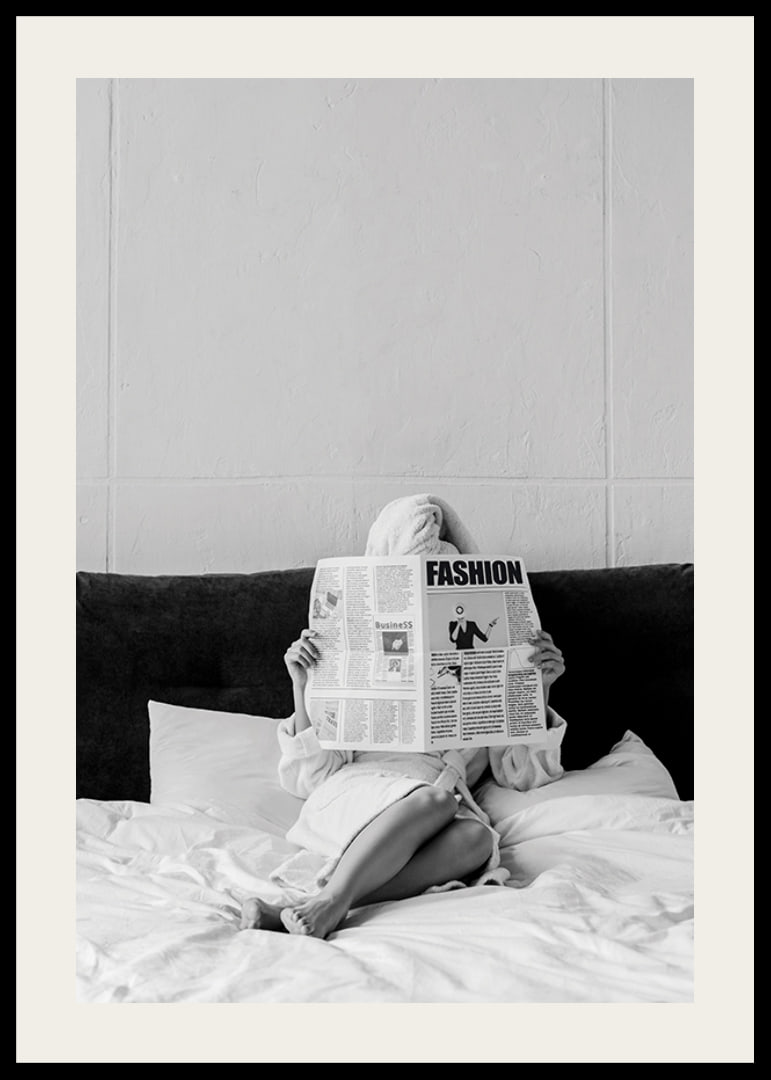 Black and white photo of woman in bathrobe reading newspaper in bed-12