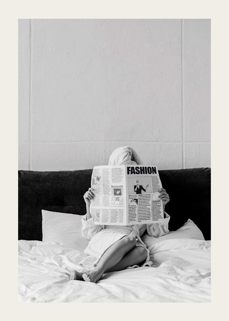 Black and white photo of woman in bathrobe reading newspaper in bed-12