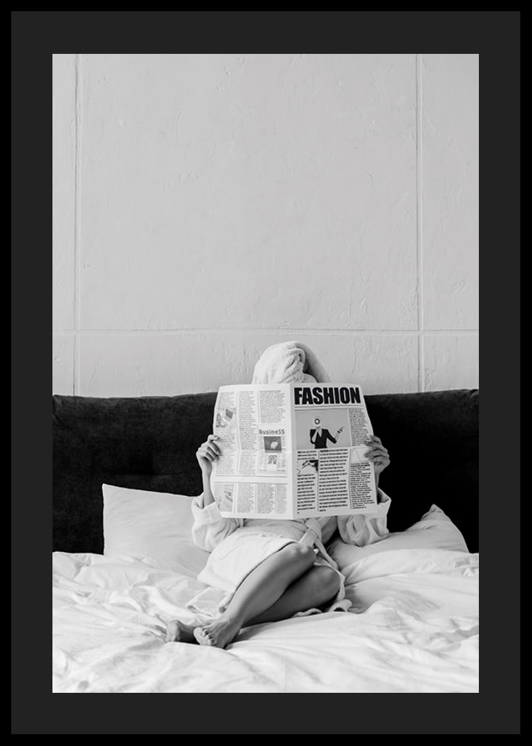 Black and white photo of woman in bathrobe reading newspaper in bed-12