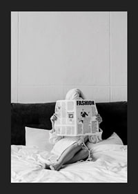 Black and white photo of woman in bathrobe reading newspaper in bed-5