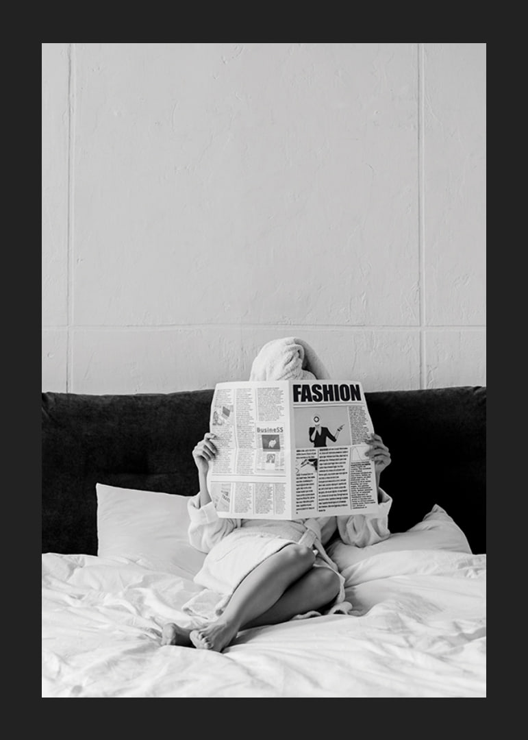 Black and white photo of woman in bathrobe reading newspaper in bed-12