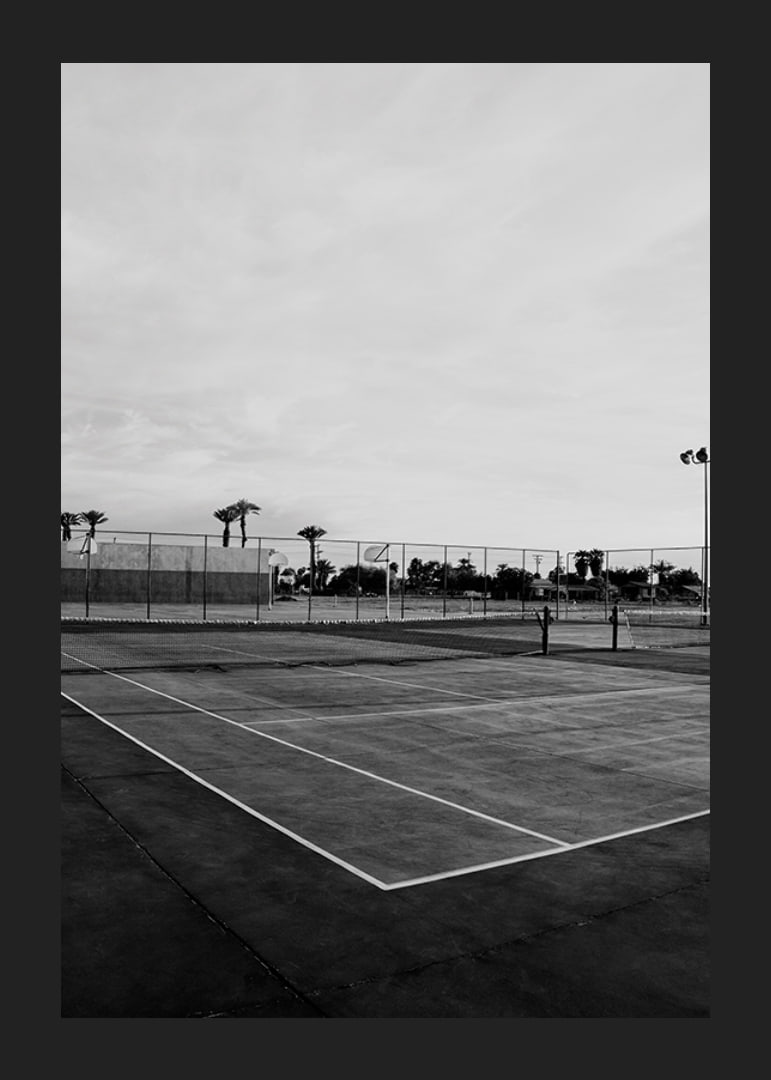 Svartvitt foto av tom tennisplan med linjer och palmträd-12