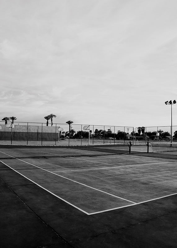 Svartvitt foto av tom tennisplan med linjer och palmträd-12