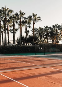 Fotografisk tennisplan med röda toner och palmer i bakgrunden-7