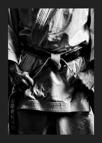 Svart-hvitt nærbilde av person i kampsportantrekk med svart belte-1