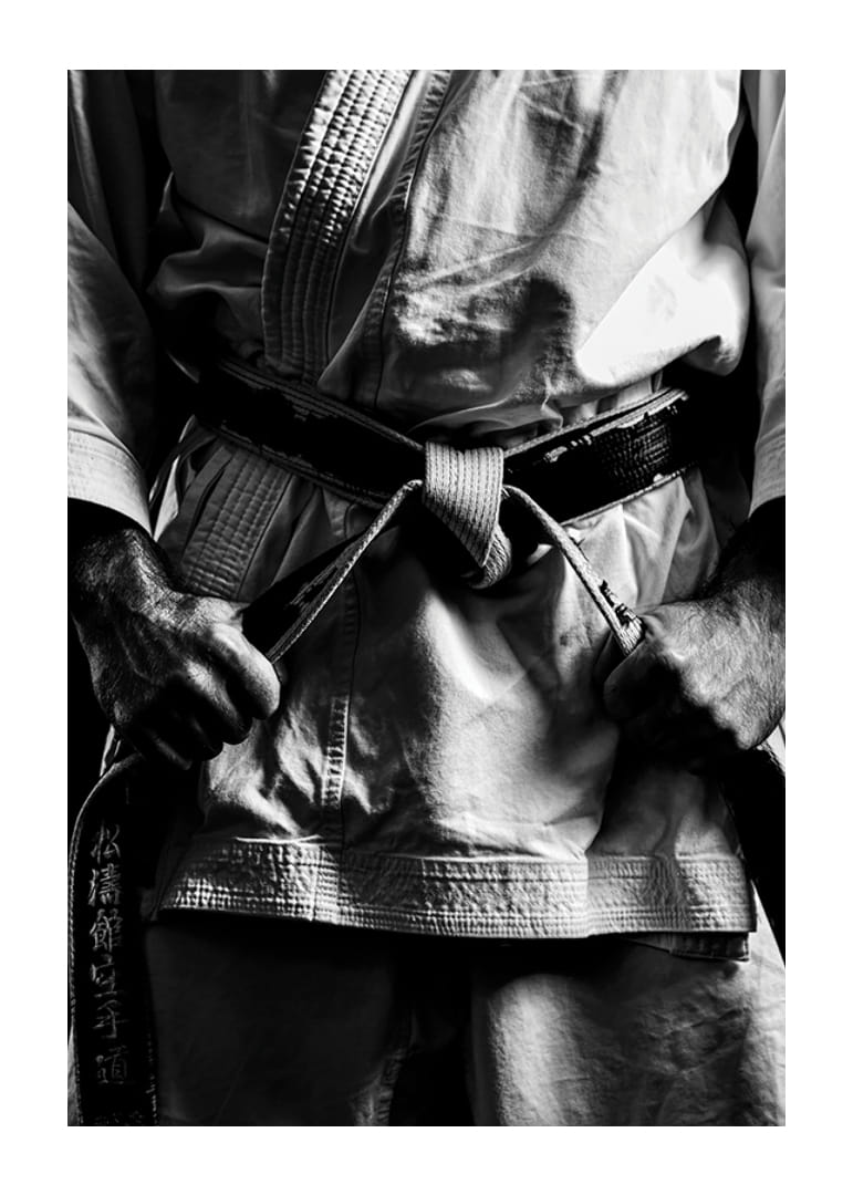 Svart-hvitt nærbilde av person i kampsportantrekk med svart belte-12