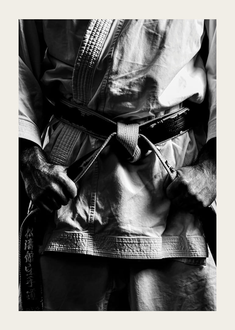 Svart-hvitt nærbilde av person i kampsportantrekk med svart belte-12