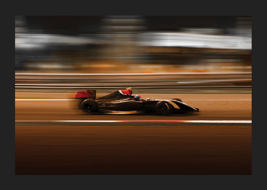 Mașină de Formula 1 la viteză mare cu fundal neclar în culori calde-12