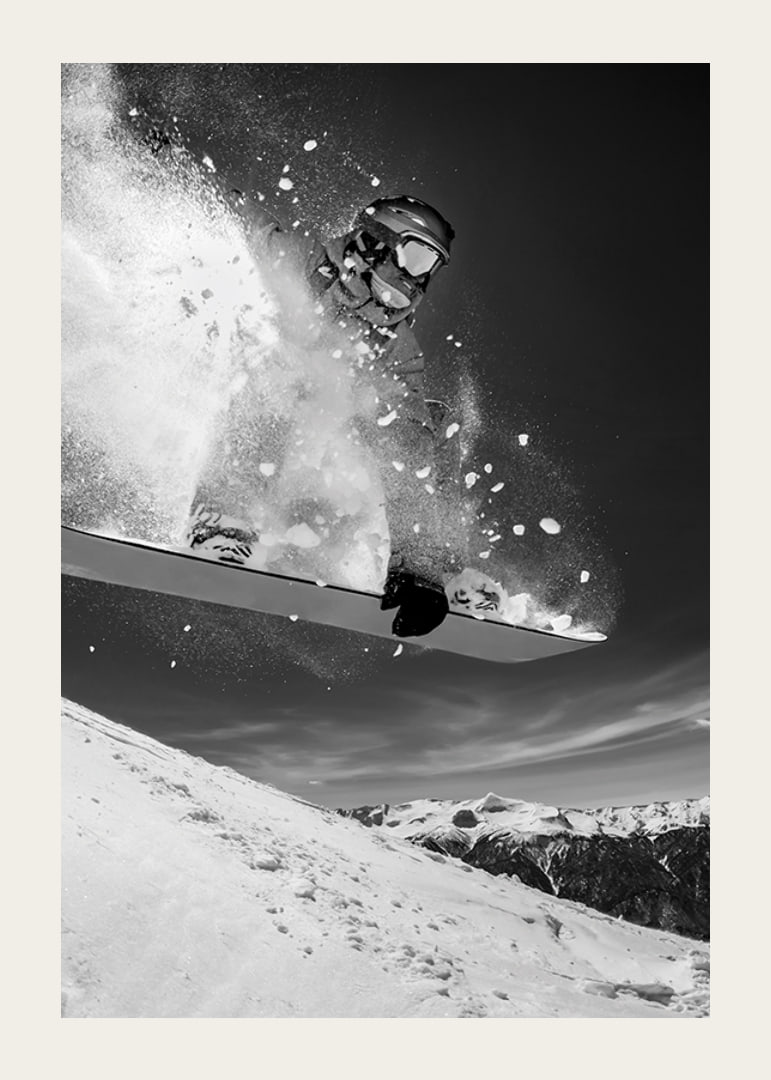 Black and white action shot of snowboarder in the middle of a jump-12