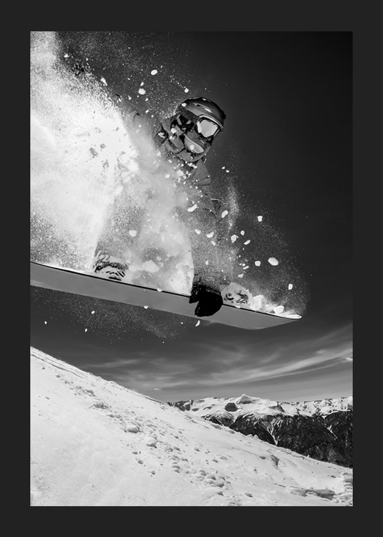 Black and white action shot of snowboarder in the middle of a jump-12
