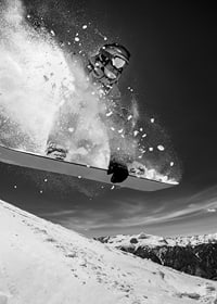 Black and white action shot of snowboarder in the middle of a jump-7