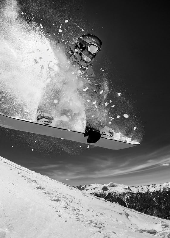 Black and white action shot of snowboarder in the middle of a jump-12