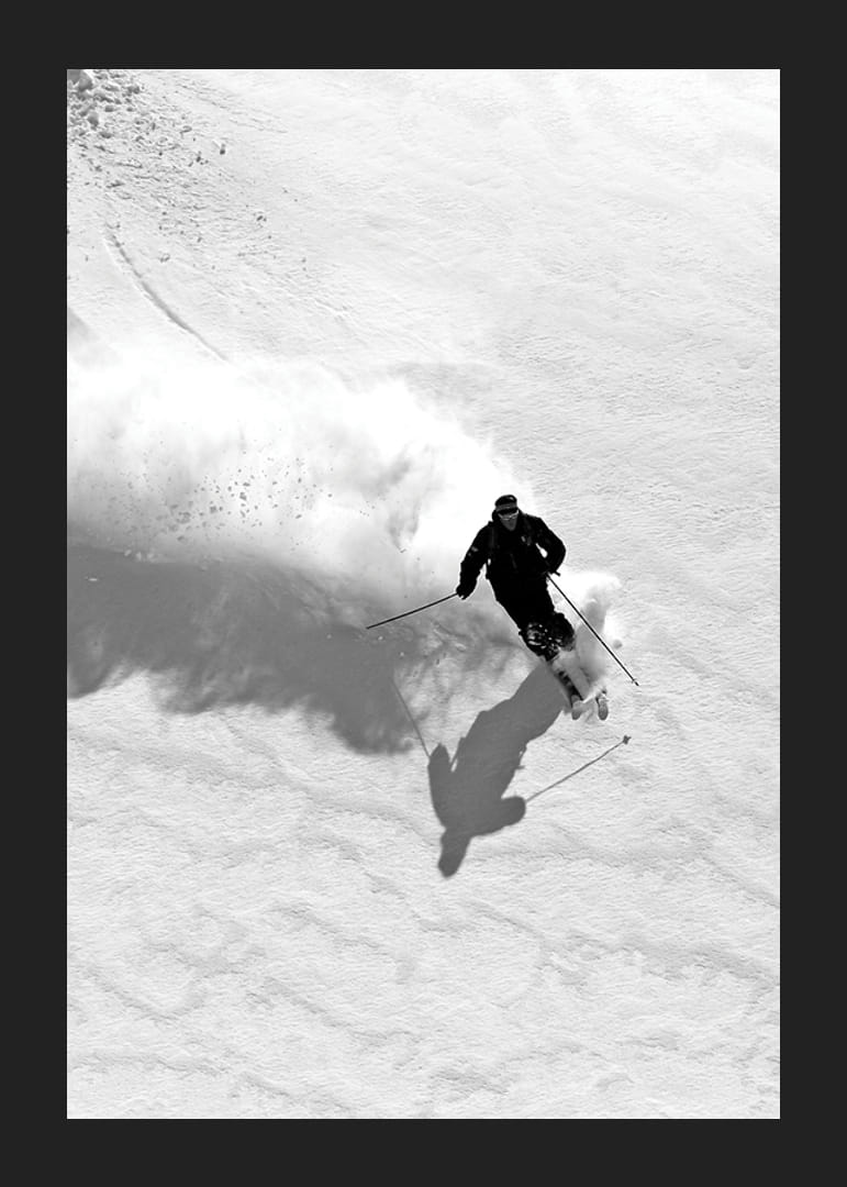 Svartvit skidåkare i rörelse nedför snötäckt fjällsida-12