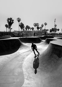 Black and white photograph of skateboarder in concrete park with palm trees-7