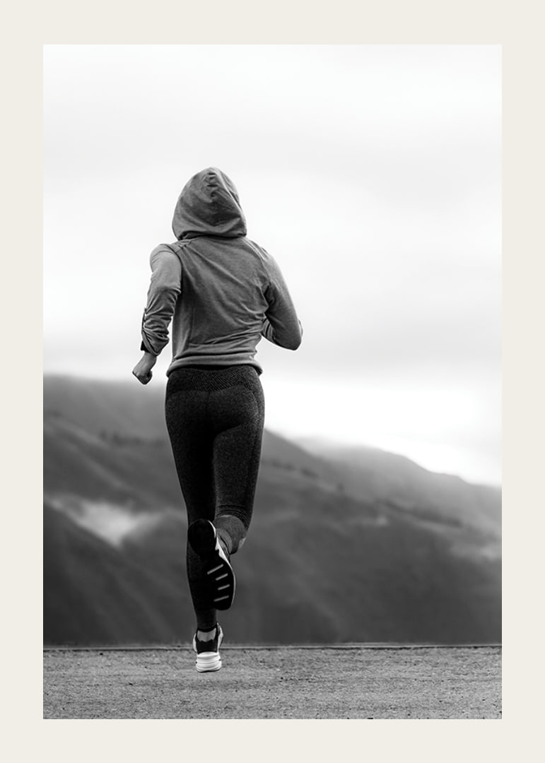 Black and white photographed woman running outdoors with mountains in the background-12