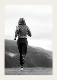 Mustavalkoisella valokuvalla kuvattu nainen juoksee ulkona vuorten taustalla-3