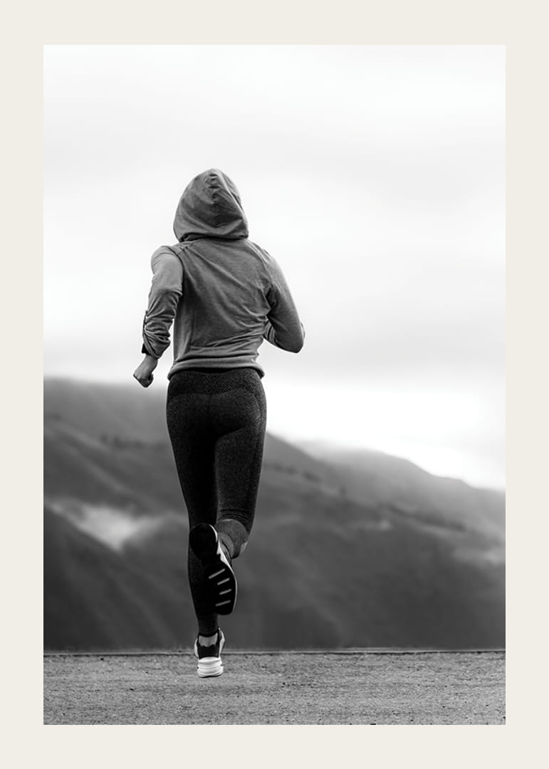 Mustavalkoisella valokuvalla kuvattu nainen juoksee ulkona vuorten taustalla-12