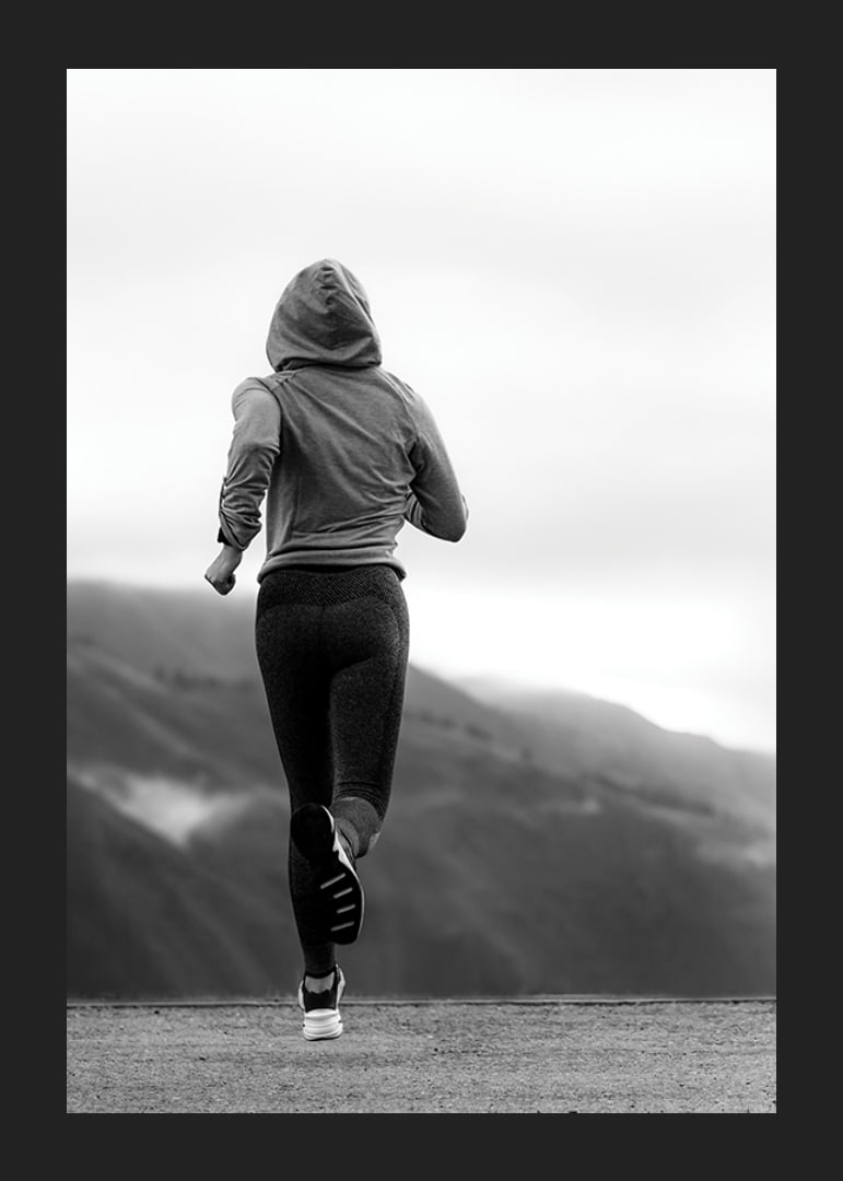 Black and white photographed woman running outdoors with mountains in the background-12