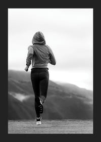 Mustavalkoisella valokuvalla kuvattu nainen juoksee ulkona vuorten taustalla-5