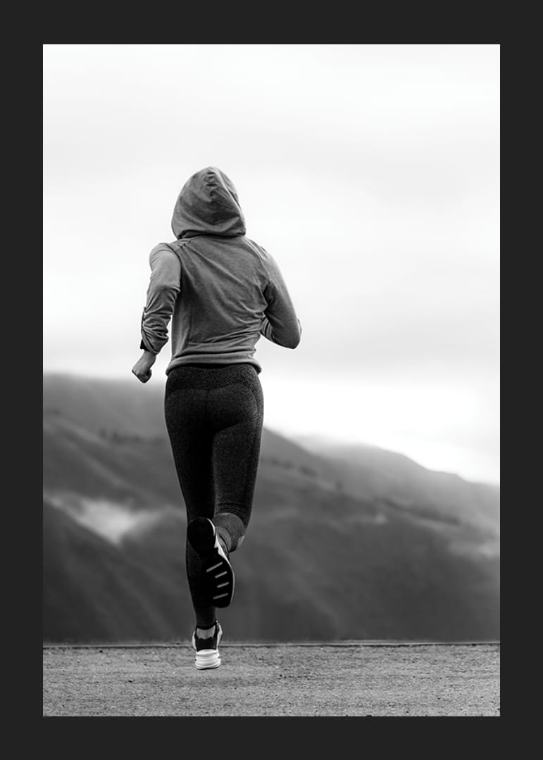 Mustavalkoisella valokuvalla kuvattu nainen juoksee ulkona vuorten taustalla-12