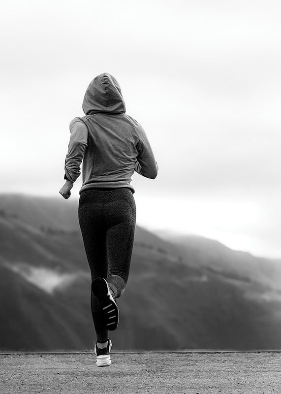 Black and white photographed woman running outdoors with mountains in the background-12
