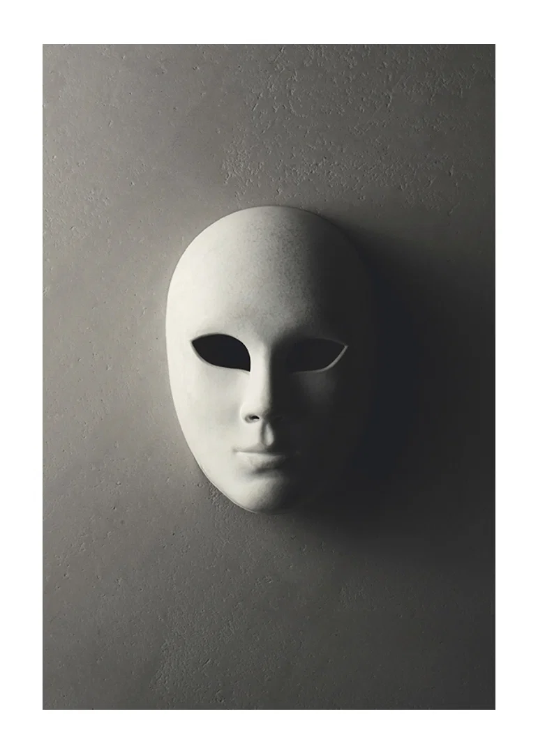 White theater mask with smooth features against gray wall in shadowy light-12