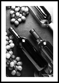 Black and white close-up of wine bottles and bunches of grapes on dark surface-2