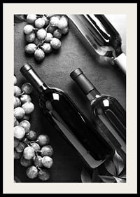 Black and white close-up of wine bottles and bunches of grapes on dark surface-4