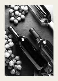 Black and white close-up of wine bottles and bunches of grapes on dark surface-5