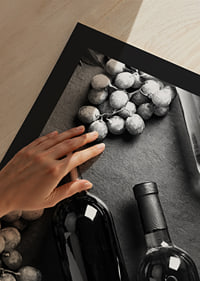 Black and white close-up of wine bottles and bunches of grapes on dark surface-9