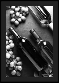 Black and white close-up of wine bottles and bunches of grapes on dark surface-4