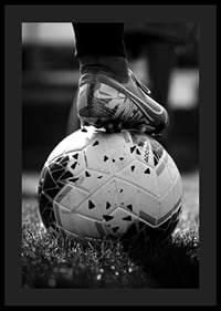 Fekete-fehér fotó egy futballcipőről, amelyet egy focilabda lábára helyeztek-0