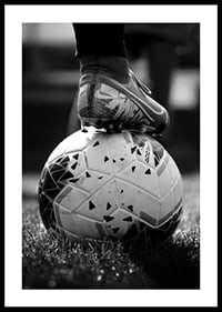 Fekete-fehér fotó egy futballcipőről, amelyet egy focilabda lábára helyeztek-2