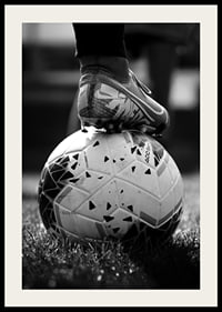 Fekete-fehér fotó egy futballcipőről, amelyet egy focilabda lábára helyeztek-4
