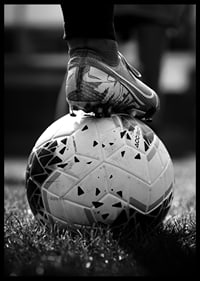 Fekete-fehér fotó egy futballcipőről, amelyet egy focilabda lábára helyeztek-6