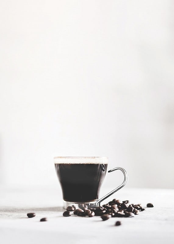 Photographic close-up of coffee glass and coffee beans, light background-12