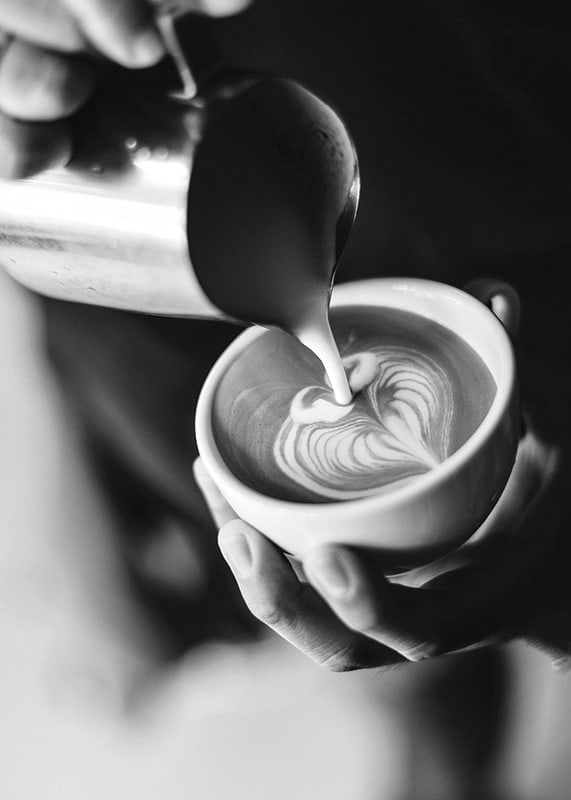 Svartvitt foto av barista som häller latteart i kopp-12