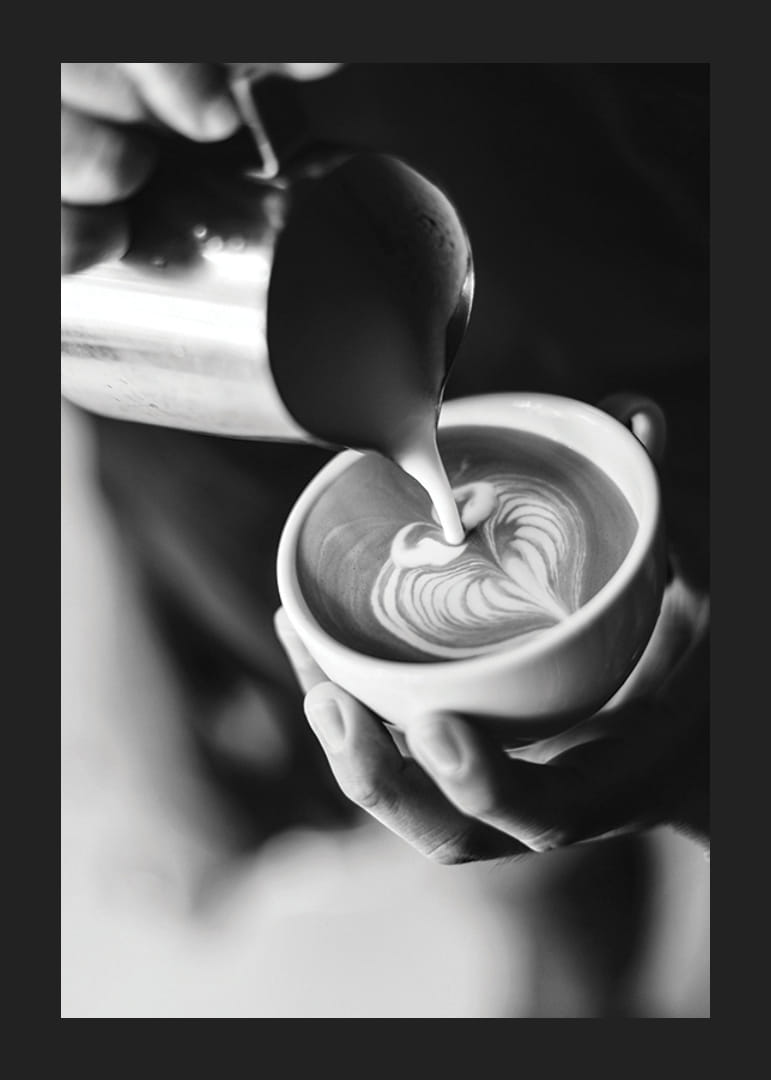 Čiernobiela fotografia baristu, ktorý nalieva latte art do šálky-12