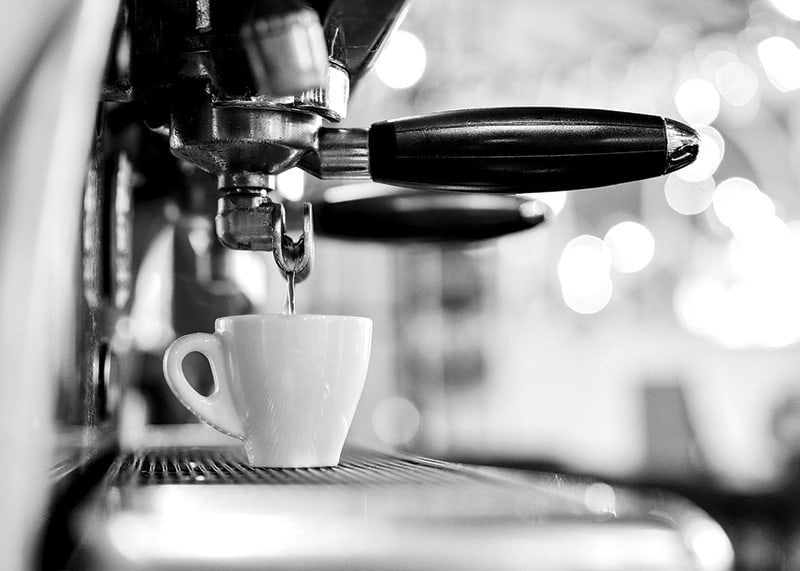 Black and white photo of espresso machine with cup during brewing-12