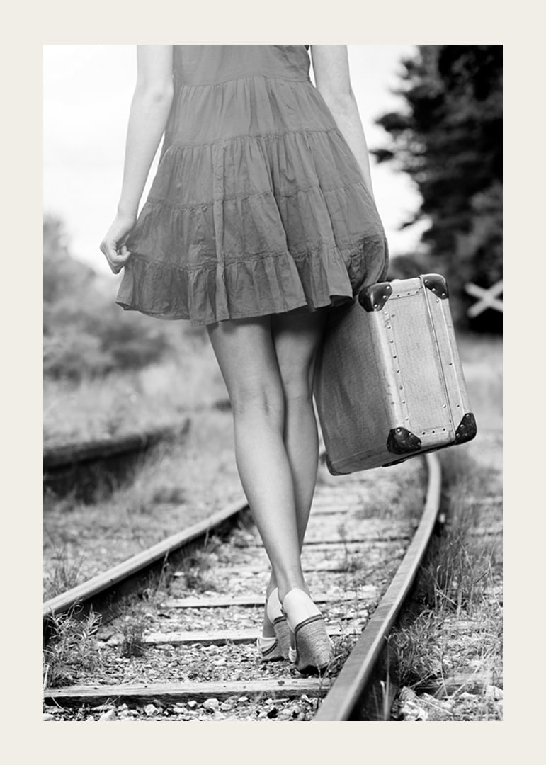 Black and white photograph of girl with suitcase on railway tracks-12
